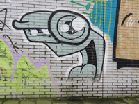 848179 Afbeelding van graffiti op een muur langs het voetpad onder de sporen aan de westzijde van het Smakkelaarsveld ...